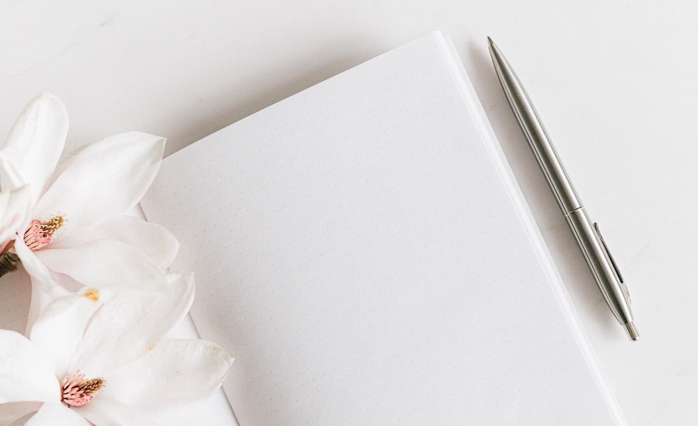 Simple white notebook with pen and flower